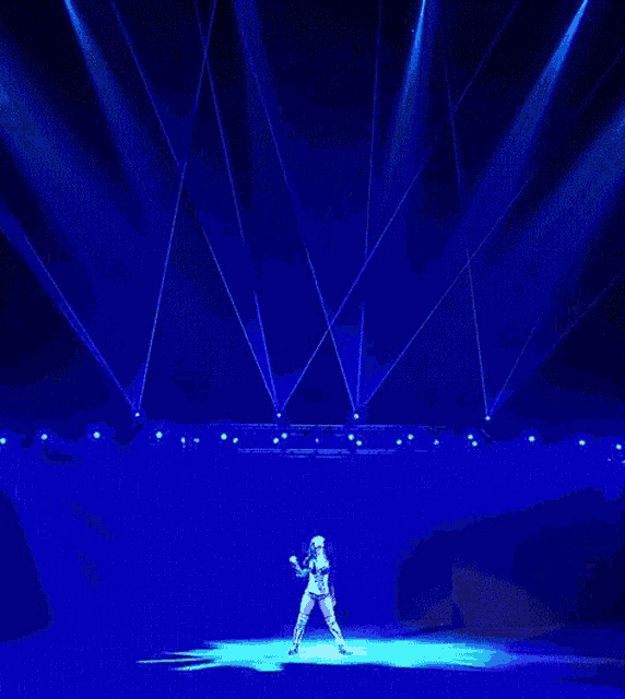 a woman is dancing on a stage with a lot of blue lights behind her