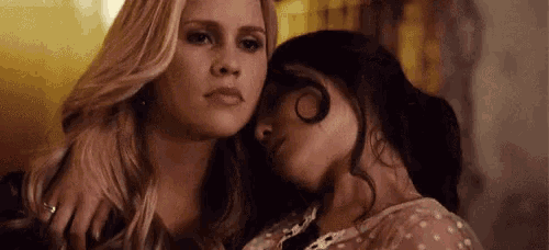 a couple of women are sitting next to each other and one of them is hugging the other .