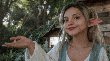 a woman wearing elf ears is holding something in her hand