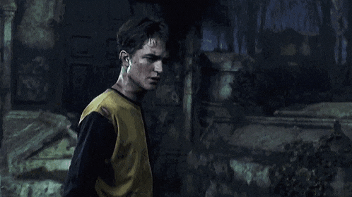 a young man in a yellow shirt is standing in a dark room .