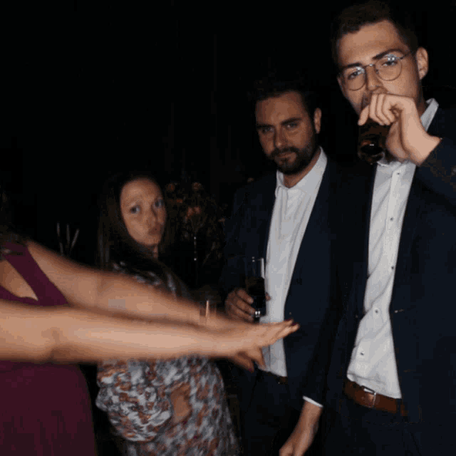 a man in a suit holds his hand to his face while a woman looks on