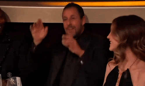 a man in a black suit says " chalamet " in front of a woman