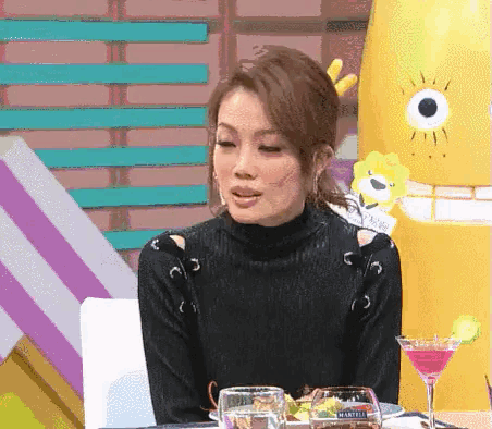 a woman in a black sweater is sitting at a table