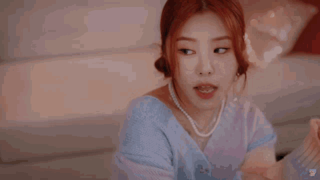 a woman wearing a colorful sweater and a pearl necklace