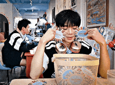 a man is sitting at a table with a basket full of stickers on his face including one that says " i love you "