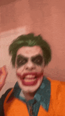 a man dressed as the joker with green hair and red lips is smiling .