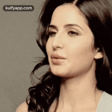 a close up of a woman 's face with a gray background and a white shirt .