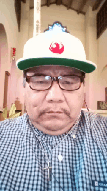 a man wearing glasses and a hat with a red star wars logo on it