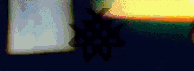 a silhouette of a person standing in front of a rainbow colored light .