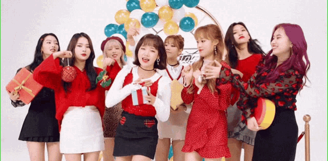 a group of girls are posing for a picture with balloons in the background and one girl is holding a gift box