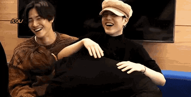 a group of young men are sitting next to each other on a couch and laughing .