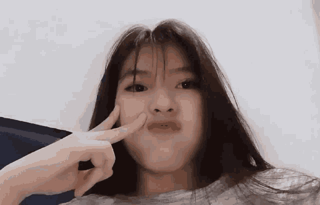 a girl with long hair is making a face with her fingers