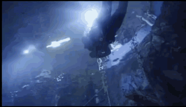 a scuba diver is swimming in the water with a light behind him