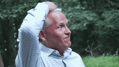 an older man is scratching his head while wearing a blue and white striped shirt