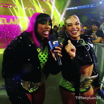 a woman with pink hair is holding a microphone while standing next to another woman