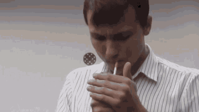 a man in a striped shirt is smoking a cigarette