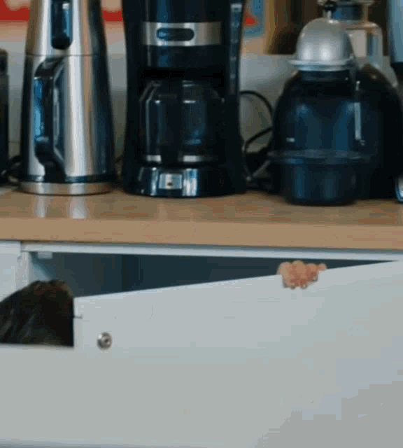 a coffee maker sits on a counter next to a kettle and blender