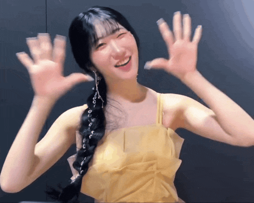 a woman in a yellow dress is smiling and waving