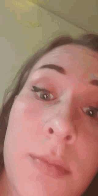 a close up of a woman 's face with a piercing in her nose and eyeliner .