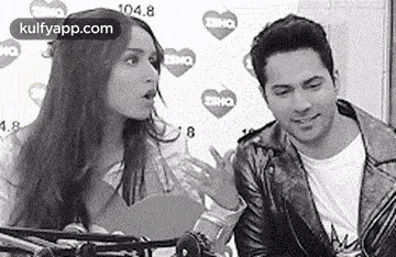 a man and a woman are talking to each other in a black and white photo . the man is wearing a leather jacket .