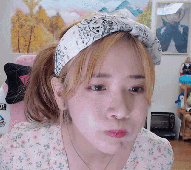 a woman wearing a headband and a floral shirt makes a funny face