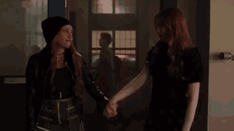 two women are shaking hands in a hallway in a room .