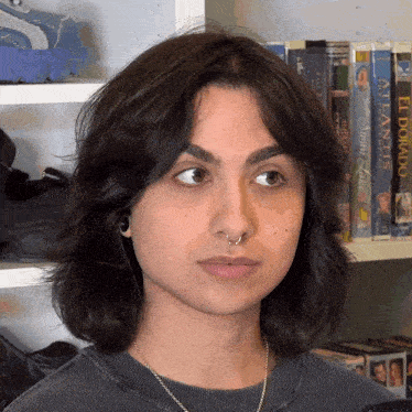 a woman stands in front of a shelf full of books one of which is titled el dorado