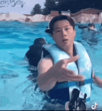 a man wearing a life jacket is standing in a pool .