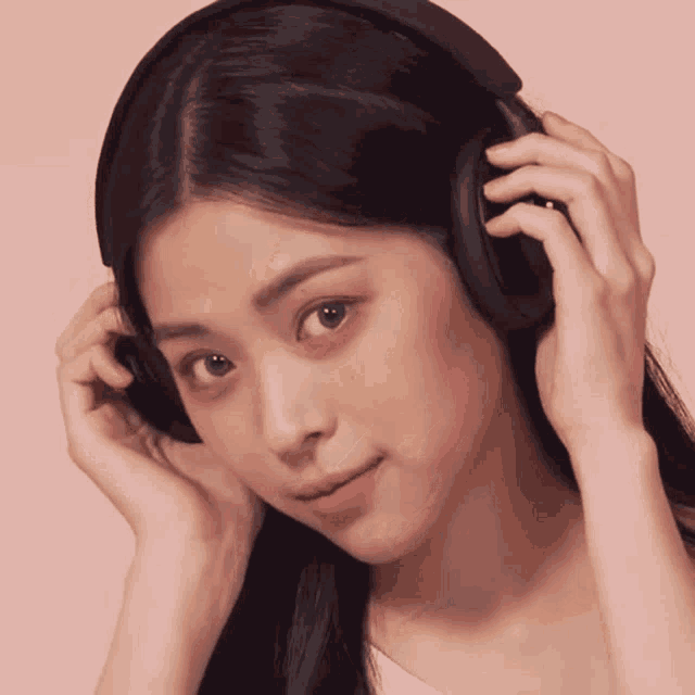 a young woman wearing headphones looks at the camera