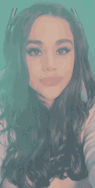 a woman with long dark hair is taking a selfie with a green background