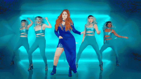 a woman in a blue dress is dancing in front of a group of dancers