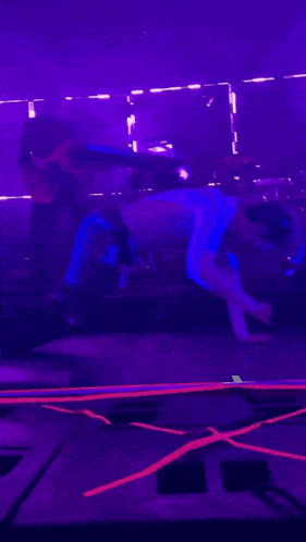 a man doing a handstand on a stage with purple lights