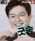 a man wearing glasses is smiling and holding a green heart shaped object .