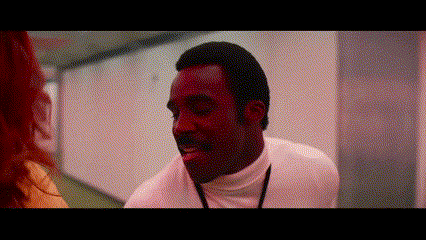 a man in a white turtleneck is talking to a woman in a red room .