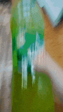 a blurred image of a person holding a green bottle