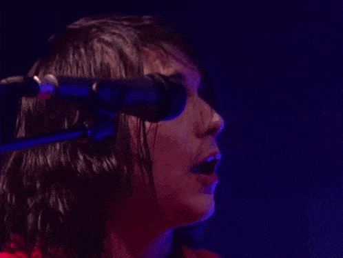 a close up of a person singing into a microphone in a dark room