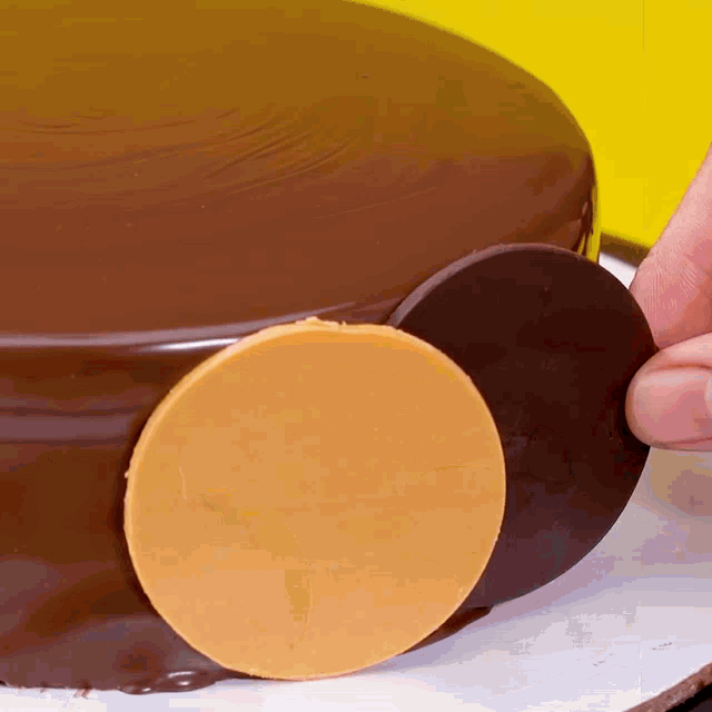 a close up of a person cutting a piece of chocolate on top of a cake