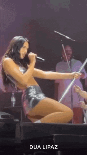 a woman is singing into a microphone on a stage while kneeling down .