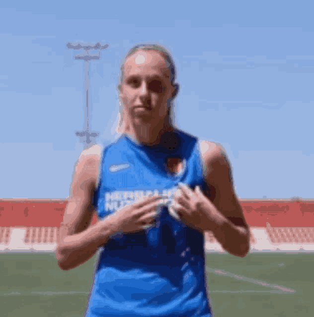 a woman in a blue tank top with herbalife on it