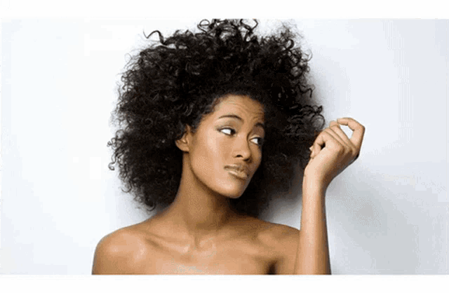a woman with curly hair is looking down at her hair
