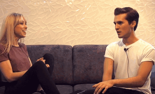 a man and a woman sit on a couch talking to each other