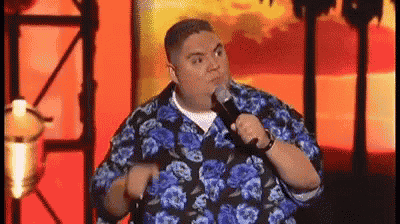 a man in a blue and black floral shirt is holding a microphone and making a funny face .