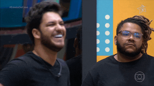 two men are laughing in front of a wall with a star on it