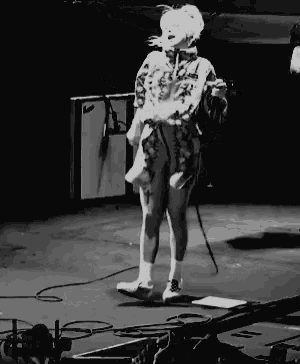 a black and white photo of a woman singing into a microphone on stage