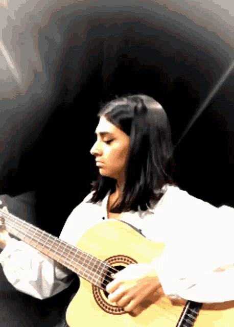 a woman playing an acoustic guitar with a black background