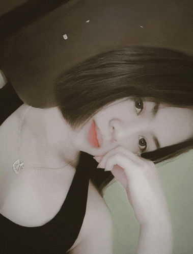 a woman wearing a black tank top and a silver necklace with a heart on it
