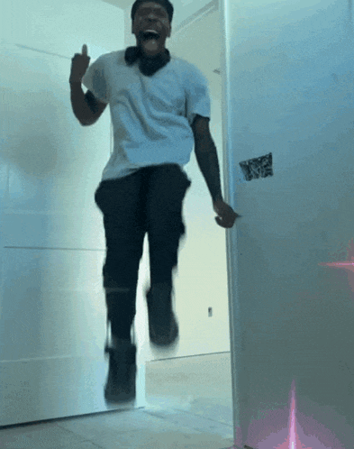 a man in a white shirt is jumping in the air and giving the middle finger