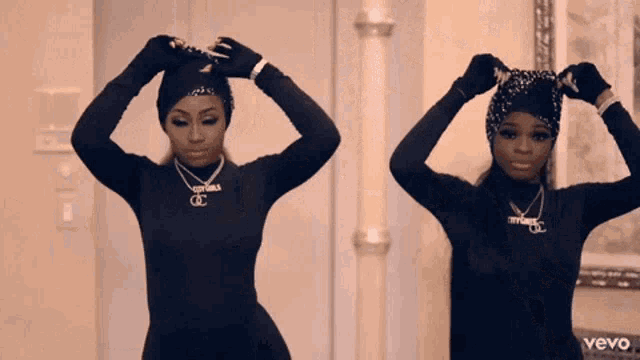 two women wearing black sweaters and necklaces with the word vevo on the bottom