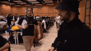 a man wearing headphones talks to another man in a room
