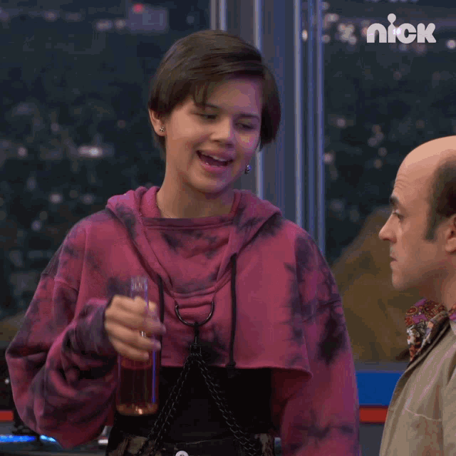 a woman drinking from a bottle next to a bald man with a nick logo on the wall behind them
